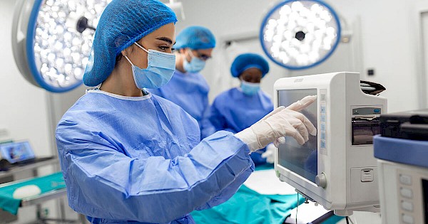 Surgeon wearing scrubs using medical equipment in operating room