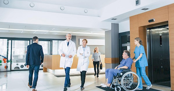 Doctors, patients, nurses, and visitors walking through hospital lobby