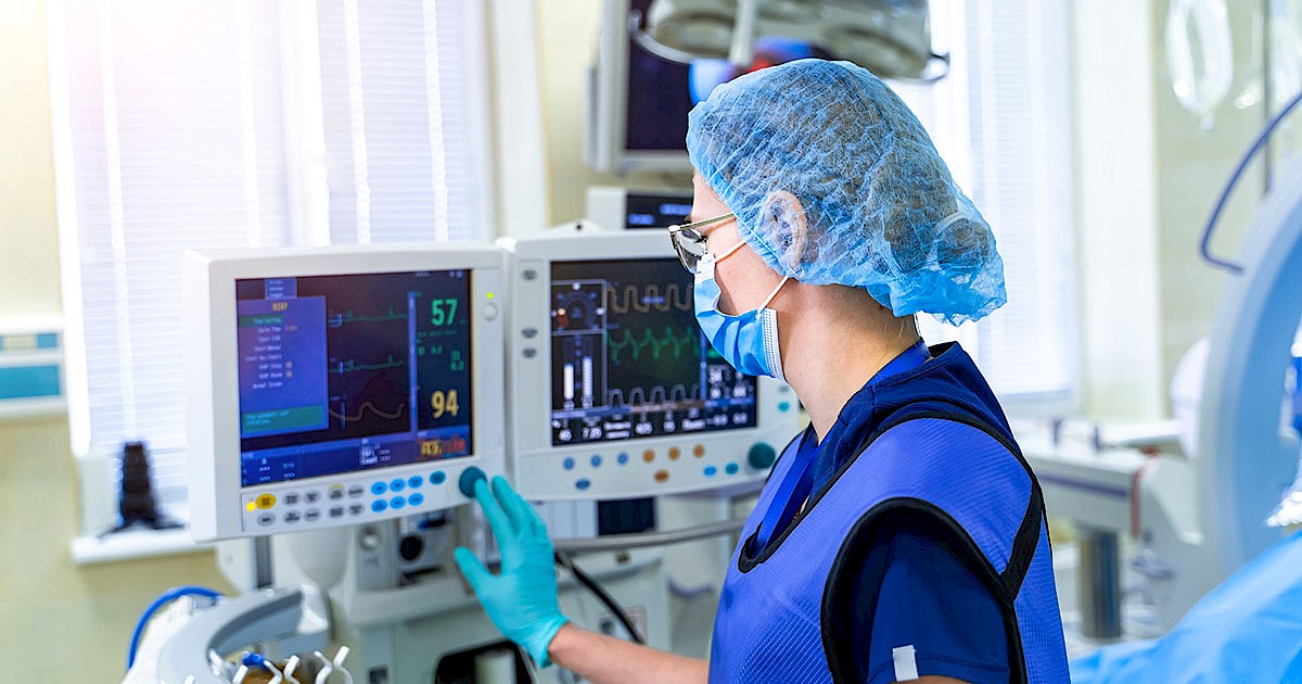Nurse in scrubs using medical equipment in hospital room