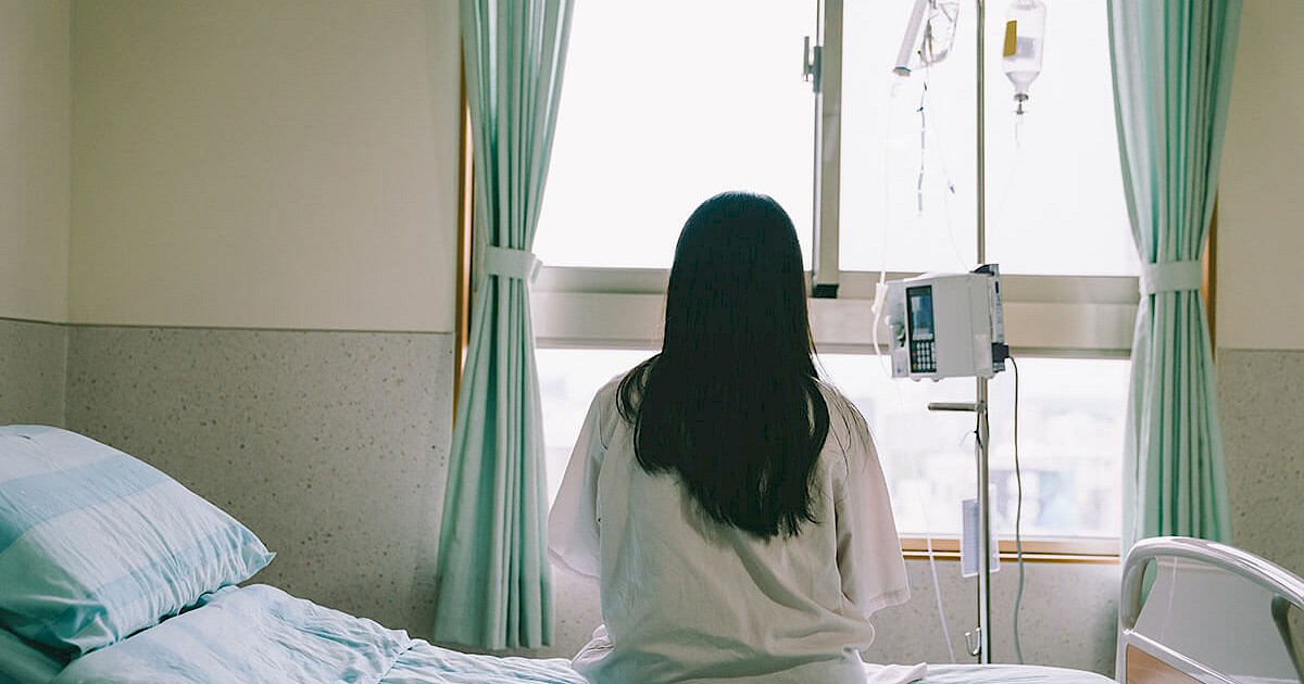 Patient sitting on hospital bed looking out window